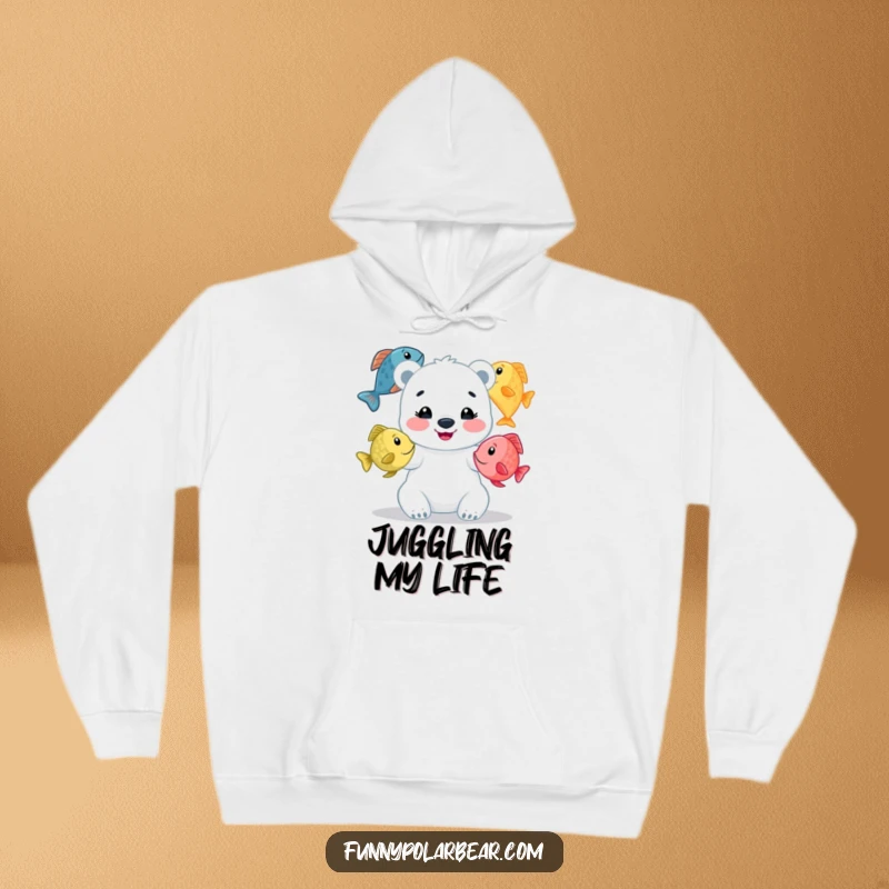 Funny polar bear cub hoodie, beaming while juggling colorful fish, a humorous and warm design for playful spirits.